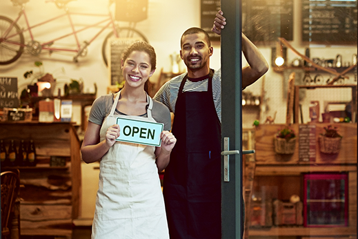 Portrait of a young man and woman holding up an open sign in their store.